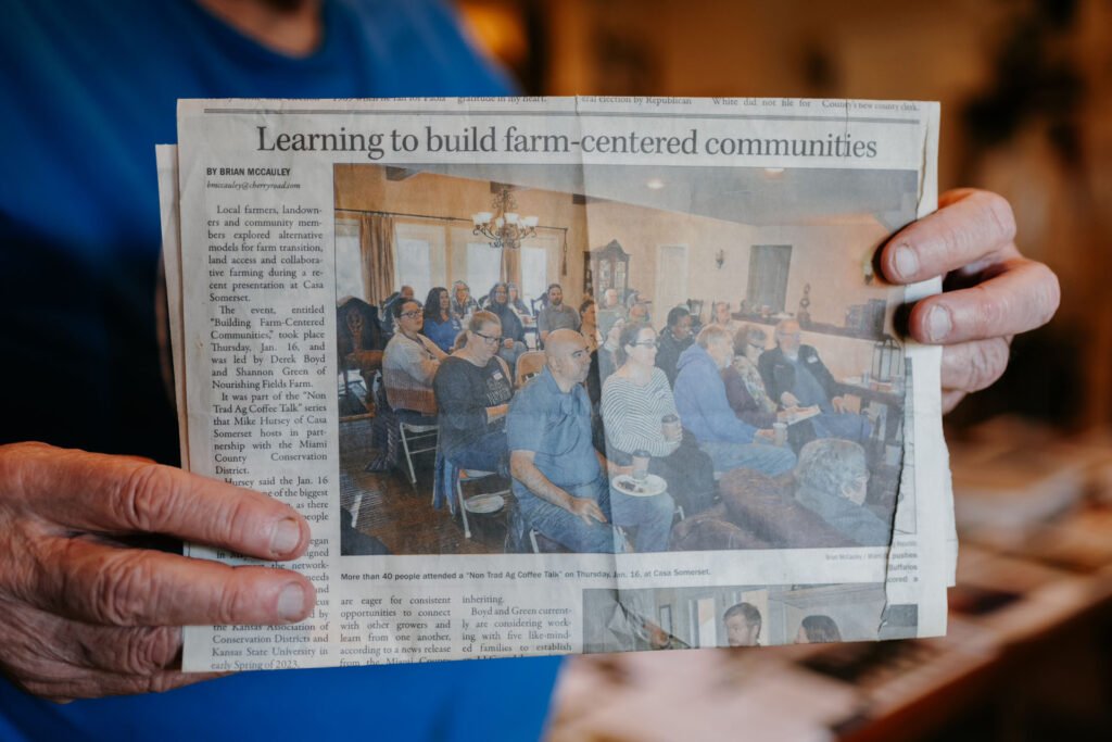 An image of a newspaper clipping being held by hands that says "Learning to build farm-centered communities"