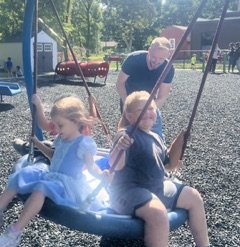Kyle Roggenkamp pushing some preschool children on a tire swing