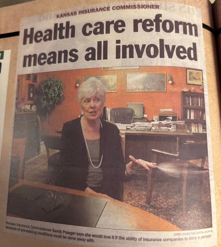 I4 SP Medicaid Ex P2 A newspaper clipping showing Sandy Praeger with the headline "Health care reform means all involved"