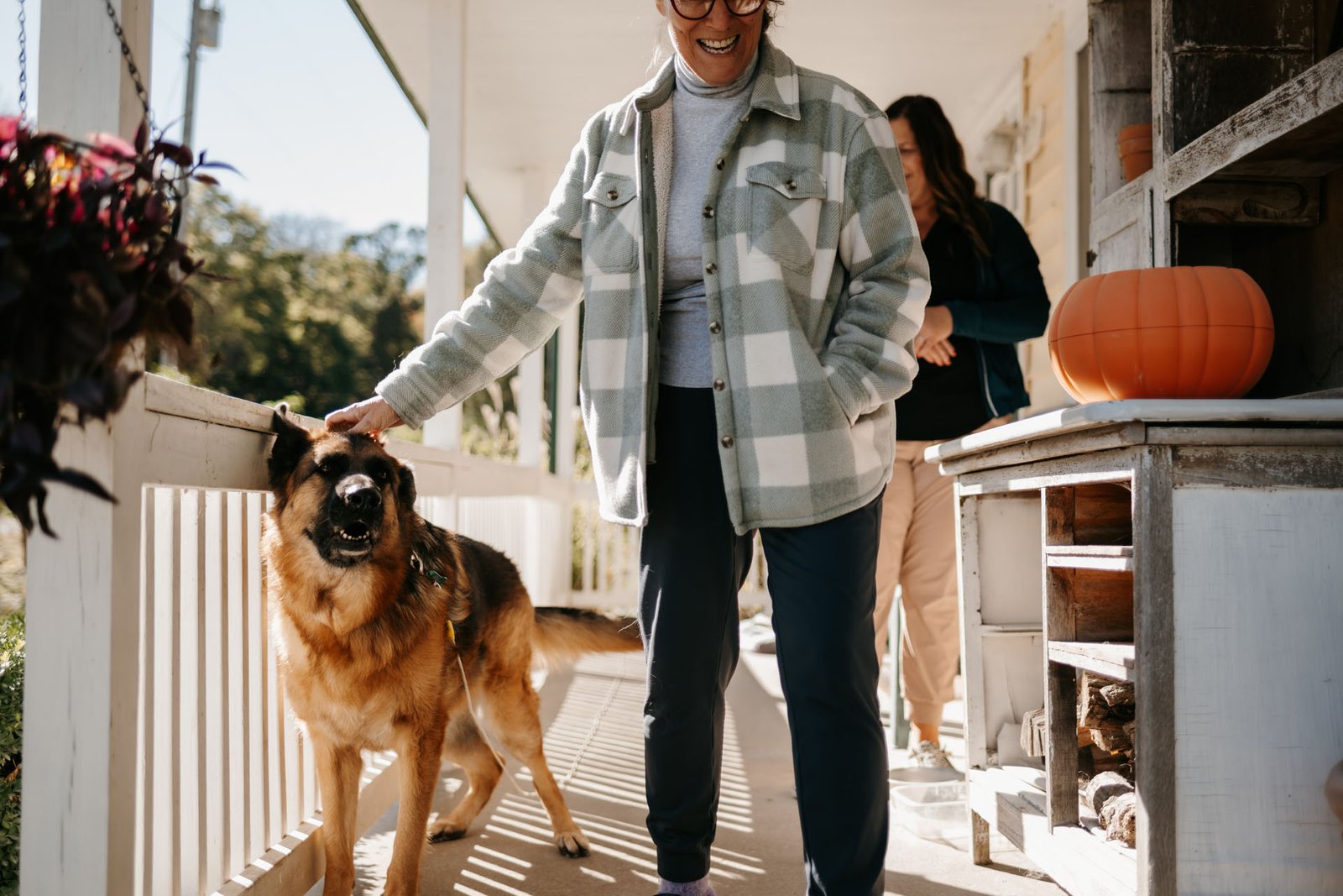 Two people standing with an attentive German Shepherd dog.