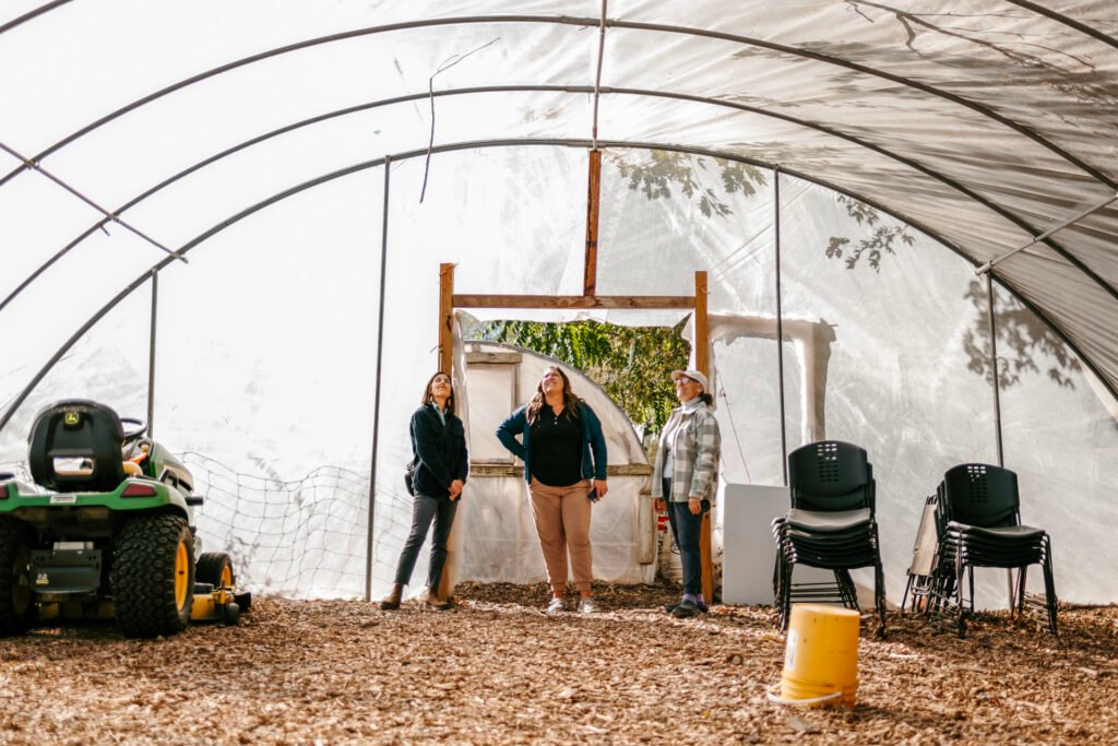 Lori Trogan and two other people standing in the distance in a greenhouse.