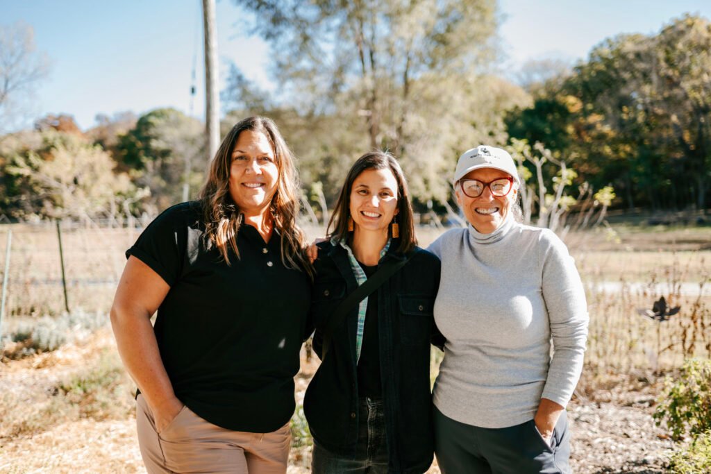 Lori Trojan and two other women with their arms around each other smiling.
