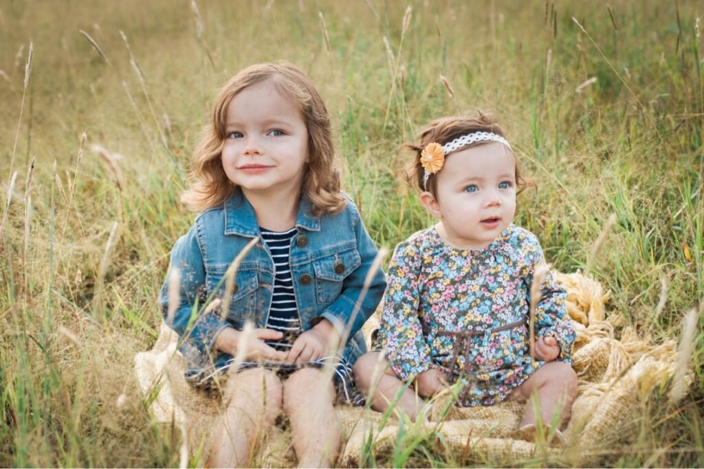 Nadine Long's two daughters sitting in a field.