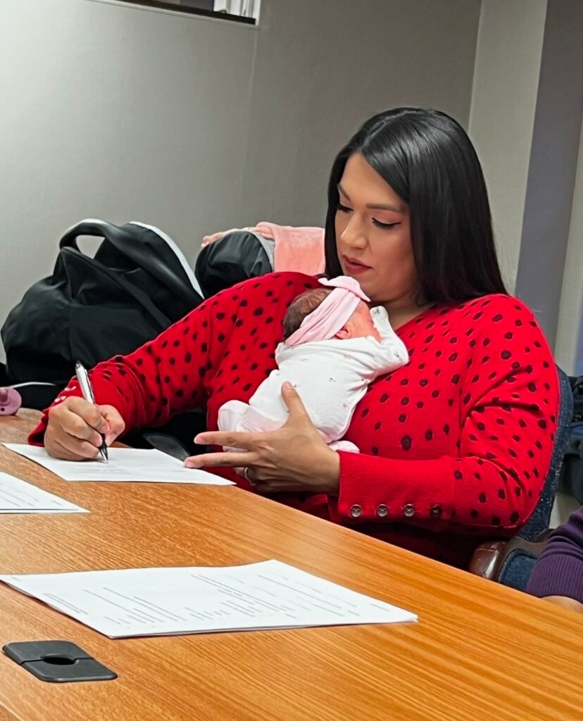 Sarah Lopez holding one of her newborn babies while wokring.